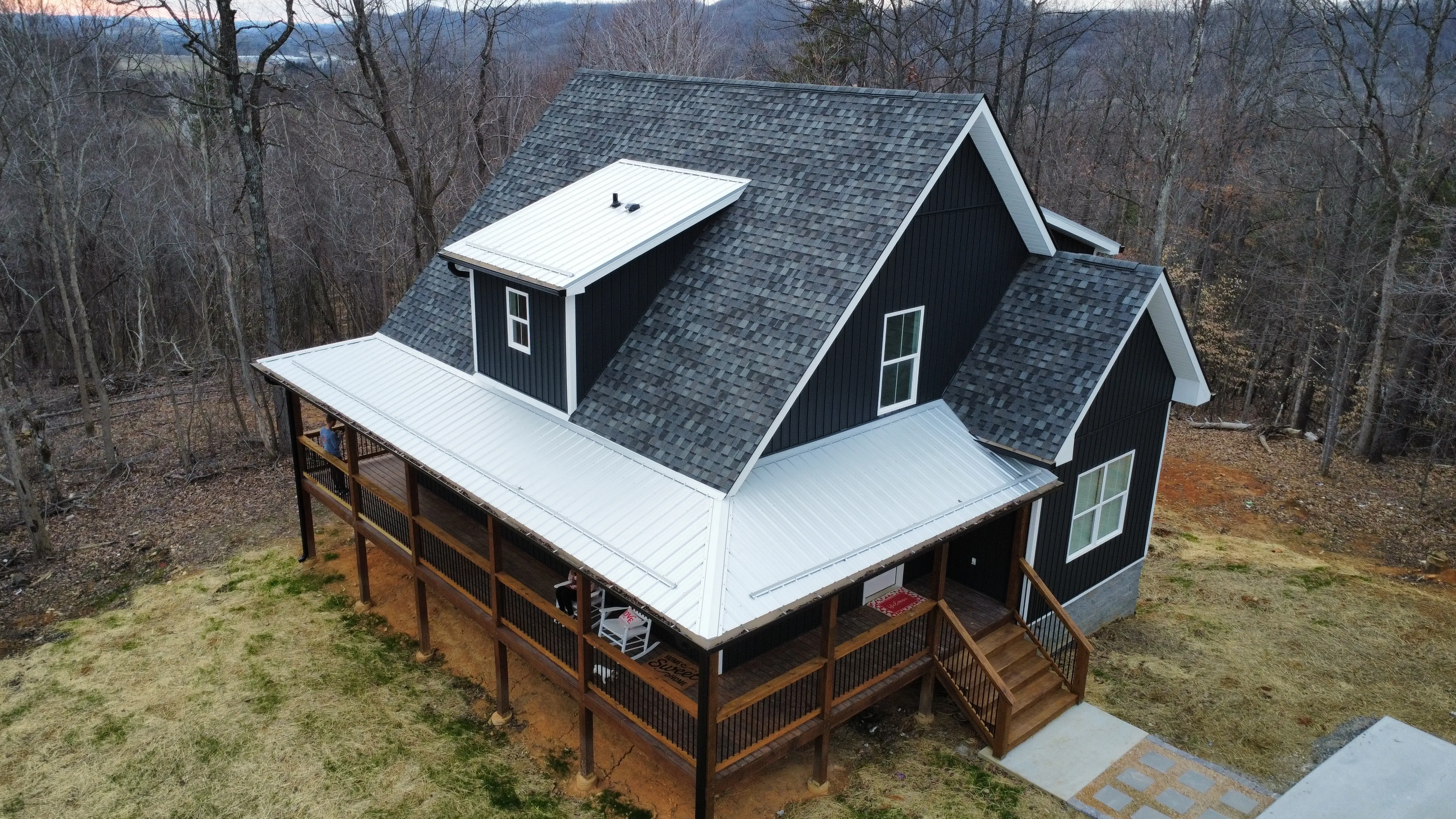 Aerial view of a black farmhouse with a new grey shingle roof and white metal porch roof in Bristol, TN