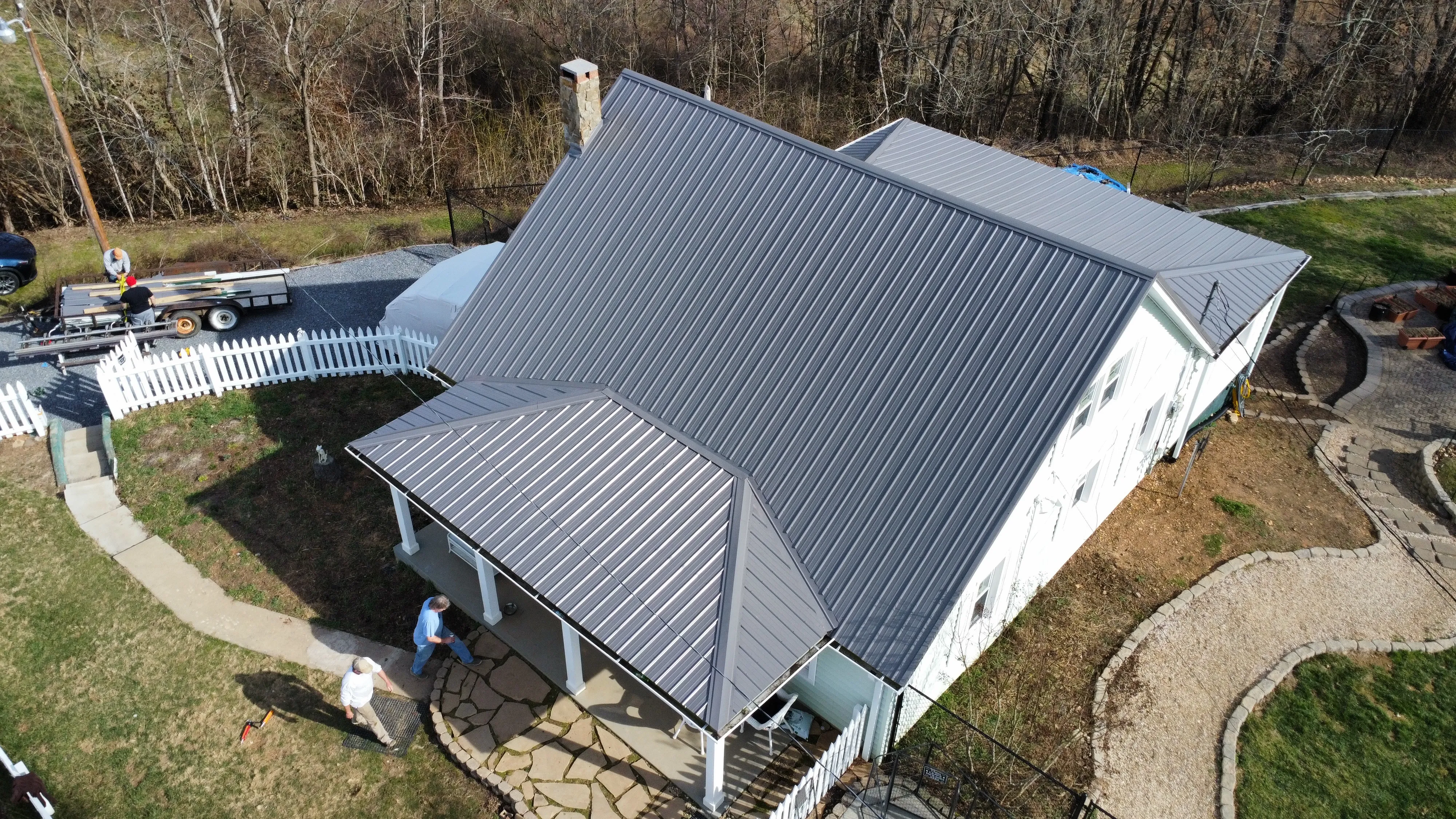 White's Roofing Co crew and truck at a white farmhouse with a new dark grey metal roof in Bristol, TN