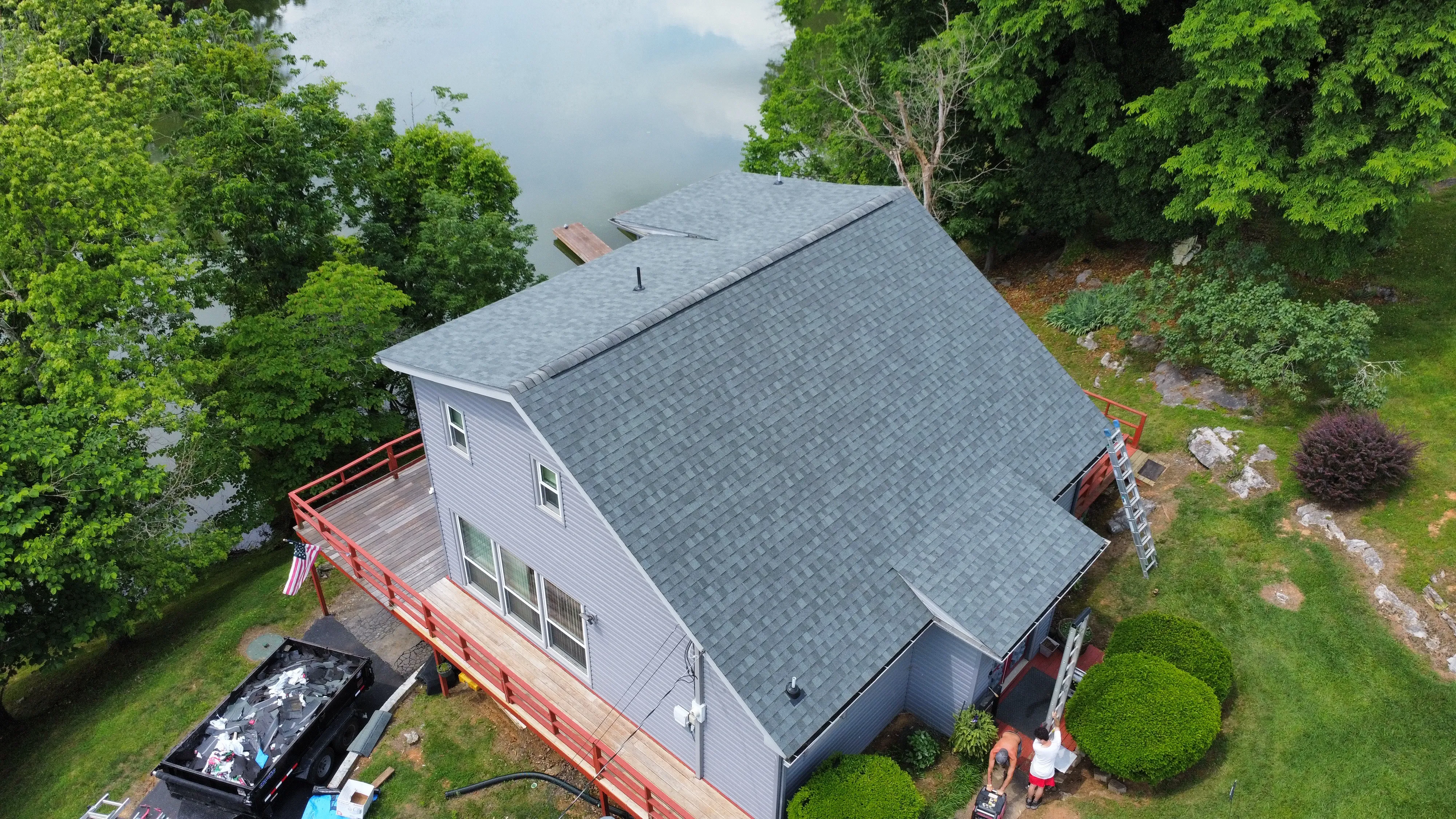 Roof replacement in progress at a lakeside home, with a tear-off debris trailer in Bristol, TN